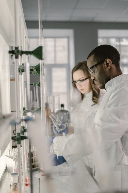 Two scientists in lab coats and safety glasses working in a modern laboratory.